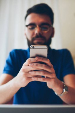 Genç hippi adam elinde cep telefonu ile bildirimi kontrol ederken aynı zamanda Wi-Fi 'ye bağlı, modern akıllı telefona odaklı yeni bir uygulama kuruyor.