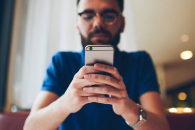 Genç hippi adam elinde cep telefonu ile bildirimi kontrol ederken aynı zamanda Wi-Fi 'ye bağlı, modern akıllı telefona odaklı yeni bir uygulama kuruyor.