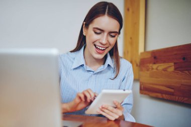 Neşeli gülümseyen hippi kız, sosyal ağdan komik espriler okuyor. Modern elektronik cihazlarda iletişim kurmak için başvuru kullanıyor. Kampüste bilgisayarla oturuyor ve Wi-Fi 'ye bağlanıyor.