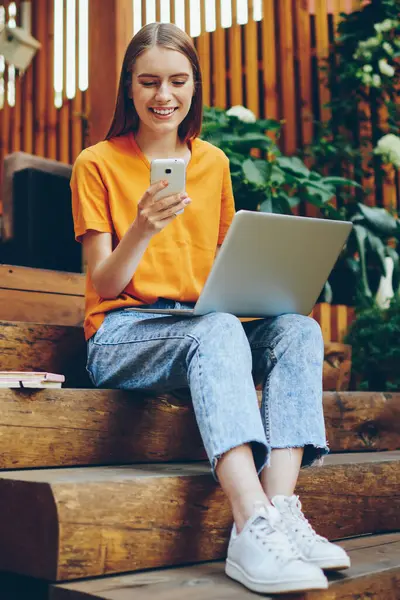 Yüzünde gülümseme olan yetenekli bir kadın blogcu takipçilerle sohbet etmek ve rahat kafeteryada eğlenmek için akıllı telefon kullanıyor. Hücresel ağda sosyal ağda iyi haberler okumaktan mutlu neşeli kadın.