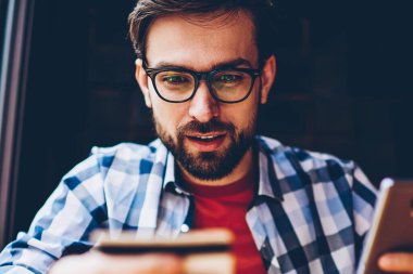 Merak optik gözlük iş smartphone aygıt üzerinde Calling kart bakarak Genç adam sakallı. Hipster adam yapma bankacılık işlem 4 g kullanarak Internet telefona bağlı.