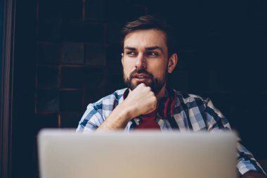 Düşünceli sakallı erkek o serbest modern dizüstü bilgisayar, kablosuz 4 g ile çalışma programı geliştirilmesi üzerinde düşünme profesyonel internet. Yayın için fikirler üzerinde durulması şaşkın genç adam