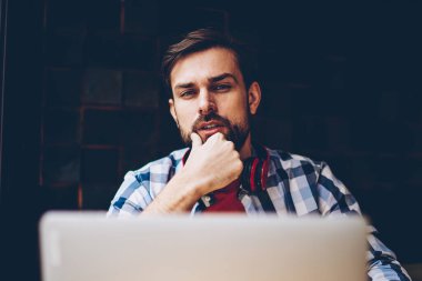 Serbest üzerinde çalışma ve dizüstü bilgisayarda kablosuz 4 g internet bağlantısı kullanarak yakışıklı sakallı hippi adam portresi. Netbook okurken kameraya bakarak boyun kulaklık ile genç adam