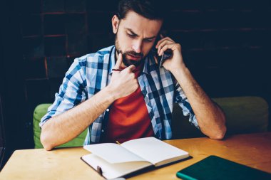 Dalgın sakallı hippi adam akıllı planı üzerinde düşünürken arama. Telefonla kafede oturan telefon görüşmesi sırasında istemci ve çözme sorunları ile konuşan genç adam konsantre