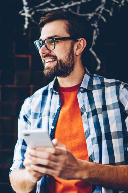 Gözlük Vizyon Düzeltme sırasında kolay mesajlaşma Smartphone cep telefonu ile 4 g internet bağlantısı ile çevrimiçi sohbette gülüyor için olumlu sakallı blogger. Neşeli genç adam üzerinde cep SMS gönderme