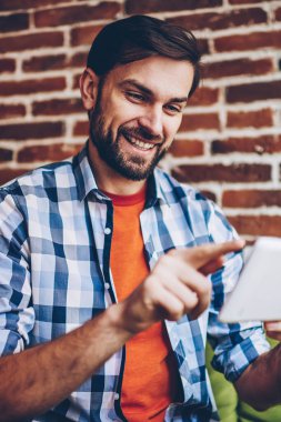 Başarılı sakallı genç adam rahat forması online sosyal ağlar üzerinden ücretsiz 4 g modern tablet sohbet metin bilgilerini yazarak giymiş Internet. Profil güncelleştirme olumlu hipster blogger