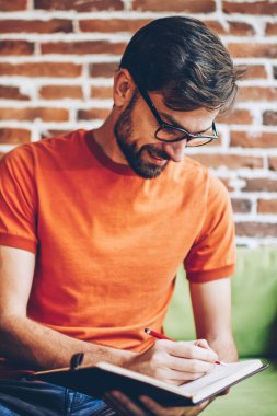 Neşeli sakallı öğrenci notlar aşağı tabii netbook aygıt ile uzay masada coworking oturan Not Defteri'nde iş yazma. Denetim listesi kayıt defterinde gözlük olumlu genç adam