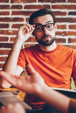 Planları ve coworking ortak başlangıç projesi geliştirmek için fikirleri tartışılması sırasında meslektaşım vizyon düzeltme uzakta iken dikkatle bakmak için şık gözlük hayran genç adam dinleme