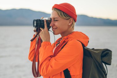 Rahat giysiler içinde, haftasonunun keyfini çıkarırken inanılmaz manzaranın fotoğrafını çeken içerikli bir kadın.