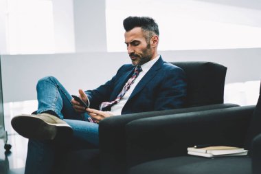 Dalgın emin işadamı bildirim koltukta oturan smartphone üzerinde okuma formal giyim giymiş. Orta yaşlı ofis çalışanı ile 4 g telefonu SMS mesaj gönderme konsantre Internet