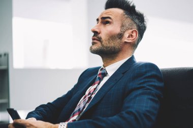 Düşünceli gurur Genel Müdür metin yanıt iletisindeki elinde smartphone ile kanepede oturan düşünürken arıyorum. Formal giyim cep ofiste sohbet olgun işadamı durulması