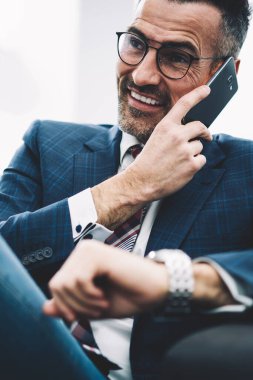 Başarılı bir girişimci orta yaşlı ofisinde oturan Smartphone cep telefonu ile telefon görüşmesi sırasında gülüyor. Zengin işadamı resmi aşınmaya cep telefonundan arıyorum. Neşeli gurur CEO'su cep üzerinde konuşuyor