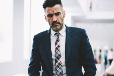 Yarım uzunluk portre başarılı emin işadamı formal giyim ayakta ofiste giyinmiş. Takım elbiseli ciddi olgun gurur CEO'su. Kameraya bakarak müreffeh orta yaşlı girişimci