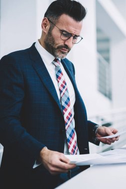 Konsantre akıllı işadamı dikkatle mali metin belgeleri okuma takım elbise giymiş. Formal giyim bilgi verilerle çalışma office metin raporları çözümleme dalgın gurur CEO'su giymiş