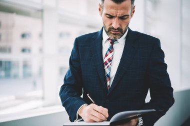 Not defteri daimi ofis iç yapım notları başarılı gurur CEO'su orta yaşlı. Kendine güvenen deneyimli olgun Finans Müdürü muhasebe belgeleri imzalama formal giyim giyinmiş