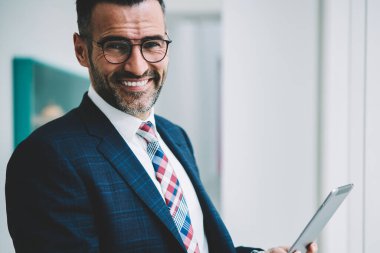 Yarım uzunluk portre resmi başarılı olgun işadamı giymek dokunmatik yüzey 4 g internet bağlantısı üzerinden ücret tahsil online yaparken kameraya gülümseyen. Tablet ile müreffeh gurur ceo