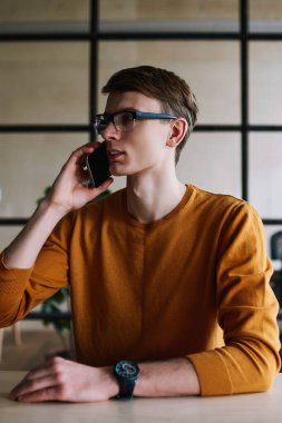 Genç, ciddi bir hippi müşteri hizmetlerinden hesap bakiyesi için telefon ediyor. Kafkasyalı erkek öğrenci cep telefonuyla 4G bağlantısı kuruyor.