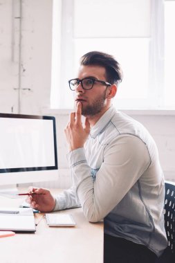 Beyaz tenli, ciddi bir erkek, internet reklamınız, teknoloji ve iletişim konseptiniz için ekran ile birlikte bilgisayarın başında otururken web sitesinde sahte olduğunu düşünüyor.