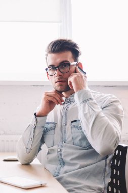 Özgüvenli erkek programcı, arka planda internet reklamınız için boş ekranlı bir evde otururken kameraya bakarak hesap bakiyesini kontrol etmek için operatörle konuşuyor.