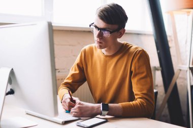 Gözlüklü genç hippi, internet sitesinden önemli web sitesini izlerken modern bilgisayardan ana bilgileri yazıyor, beyaz adam sosyal ağda teknolojiyle haber okuyor.