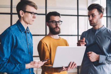 Bir grup yeniyetme genç adam dizüstü bilgisayarla dosya indirirken 4G internete göz atıyorlar, Kafkasyalılar modern ofiste işbirliği yapıyorlar ve netbook bilgisayarında çalışmak için uygulama yüklüyorlar.