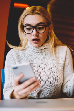 Şok olmuş ağzı açık bir kadın, elinde akıllı telefonuyla faturasını ödediği için şaşırdı. Duygusal kadın, hücresel sorunlardan kaynaklanan kötü haberleri okuyarak streslendi.