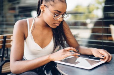 Ciddi bir Afro-Amerikalı kadın elinde dijital tabletle internetten sohbet etmek için mesaj yazıyor. Konsantre Afro-Amerikan kadın blogcu gelir e-postalarını ve bildirimlerini kontrol ediyor.