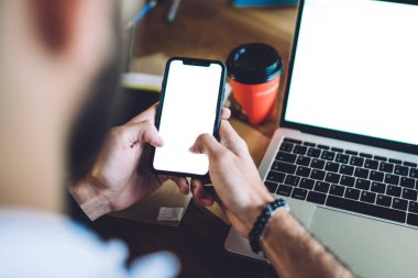 Modern cep telefonu kullanan meçhul işadamlarından. Kafede dizüstü bilgisayarlı ve kahveli ahşap masada otururken.