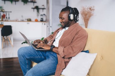 Kulaklıklı mutlu erkek programcı internet üzerinden ağ üzerinden ev içi internet bağlantısını kullanıyor modern dizüstü bilgisayar ağı sosyal medyası olan neşeli yetenekli bir adam.