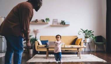 Tatminsiz bir çocuğun modern yaşam alanında yakalandığı otantik ebeveynlik anı. Baba ve çocuk çağdaş iç mekanda anlamlı bir diyalog içinde. Sarı kanepe ve minimalist dekor.
