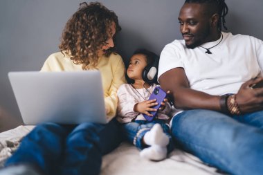 Haftasonu ev içinde çeşitli karı-koca, dizüstü bilgisayarlı ve elektronik kulaklıklı küçük kız çocuğuyla konuşurken birden fazla iş ve çok ırklı aile bağı kavramı