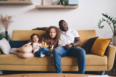 Haftasonu televizyon prizmasından kameraya bakan çeşitli aile portresi, duygusal evlilik ve oturma odasında boş zamanlarında muz izleyen kıvırcık kız.