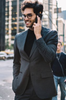 Manhattan şehir merkezinde yürürken akıllı telefondan konuşan mutlu genç işadamı, resmi giyinmiş başarılı bankacı ve cep telefonu teknolojisiyle iletişim kuran gözlük