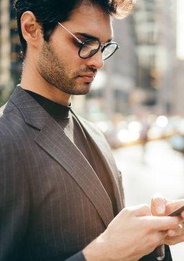 Resmi giyinmiş şık genç işadamı, megalopolis şehir merkezinde bulunan 4G internet bağlantısı üzerinden akıllı telefondan sohbet ediyor, başarılı bir avukat, sokakta cep telefonuna cep telefonu ile yazı yazıyor.