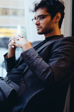 Düşünceli erkek ekonomist resmi giysiler içinde dijital netbook üzerinden yüksek hızlı internet bağlantısı üzerinden özel ders izliyor, kafenin içinde oturuyor, iş adamlarının internet üzerinden haberleri okuduğunu düşünüyor.