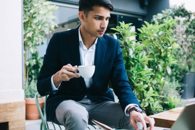 Zengin iş adamı 20 'li yaşlarda moda kıyafetleri içinde internetten kahve fincanı tutan videolar izliyor, ciddi bir erkek milenyum girişimcisi haberleri okuyor ve kafeterya terasında postaları kontrol ediyor.