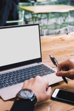 Lüks kol saati olan zengin işadamının görüntüsü. Kafenin iç kısmında oturan, uzaktan çalışan, erkek serbest çalışan, dizüstü bilgisayarında web sayfasını inceleyen, ekran görüntüsü hazırlayan.