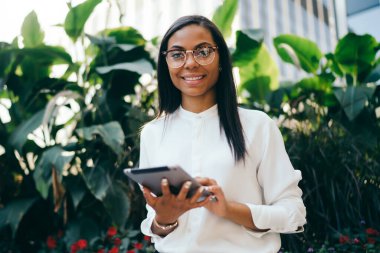 Başarılı koyu tenli kadın ofis çalışanı dijital dokunmatik ped cihaz üzerinde online ödeme yapmadan Eyewear portresi bağlı 4 g için Internet. Tablet ile müreffeh Afrikalı-Amerikalı genç kadın