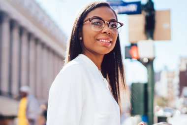 Smartphone ve klasör kamera ayakta Üniversitesi tarihinde karşı sokağında gülümseyen elinde tutan Hukuk Fakültesi başarılı koyu tenli öğrenci portresi. Cep ile pozitif kadın işçiye