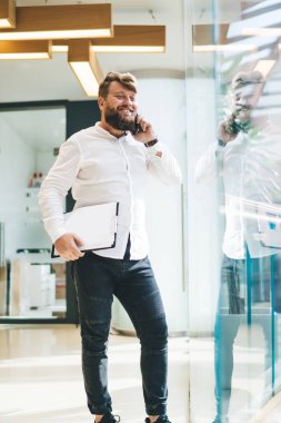 Neşeli, müreffeh, beyaz erkek yönetici cep telefonu görüşmeleri sırasında gülümsüyor, başarılı gururlu CEO, şık günlük kıyafetler giyiyor akıllı telefon görüşmeleri yapıyor ofiste proje için iyi fikirler paylaşıyor.