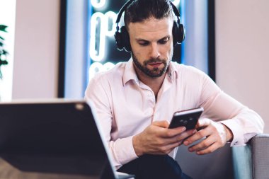 Elektronik teçhizatta Kafkasyalı serbest çalışan uzaktan kumandalı iş kitabı 4G kablosuz bağlantısını modern cep telefonu teknolojisi için kullanan adam web bankacılığı için bilet ayırtıyor.