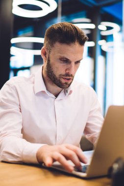 Sosyal ağlarda dizüstü bilgisayar paylaşımı yayınında yazan zeki serbest çalışan, internetten iş arama ve orta web sitesinden dosya indirmek için modern netbook kullanan beyaz bir adam.