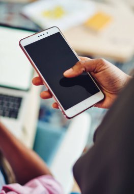 Cep telefonunu dinleyen yüzü olmayan ve bilgisayarlı meslektaşı modern ofisteki bulanık arka plandan...