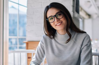 Kafeteryada kameraya bakan gülümseyen genç bir kadının portresi, 4G bağlantısı olan yeni bir telefon blogu, modern cep telefonu kullanan neşeli bir hippi kız ve uygulama üzerinden kısa mesaj gönderen bir kız.