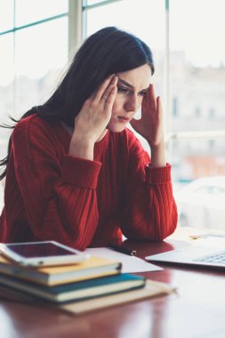 Kafası karışmış bir kadın, modern dizüstü bilgisayarını evde kötü dersler izlemek için kullanıyor, kafeteryada oturan, kafkasyalı, mutsuz, hippi bir kız ve online çalışmak için yeni bir ağ kitabı kullanıyor.