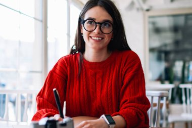 Neşeli başarılı bayan öğrenci, kafeteryada kafeterya hakkında düşünürken, yan tarafa bakıyor. Gözlüklü mutlu hippi kız, üniversite kütüphanesinde tatlı bir gülümsemeyle öğreniyor.