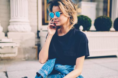 Cep telefonuyla arkadaşını arayan çekici bir kadın şehir merkezini yeniden inşa ederken uygulamayı kullanıyor. Hippi kız sıradan bir kot pantolon giyiyor. Açık havada gelişmiş bir telefonla konuşuyor.