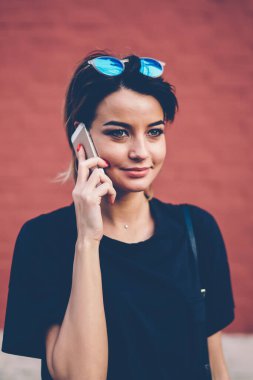 20 'li yaşlarda, güneş gözlüklü, elinde cep telefonu olan ve uluslararası arama yapan, modern teknoloji ve milenyum yaşam tarzı kavramını benimseyen bir genç kız.