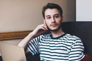 Düşünceli, akıllı bir adam dizlerinin üzerinde çalışıyor, yanakları destekliyor, koltuğun sapında dinleniyor ve ara veriyor.