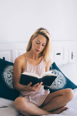 Sarışın, ipek pijamalı genç bayandan çapraz bacaklı yatağa oturmuş Barcelona 'da güneşli bir sabahta kitap okuyordu.